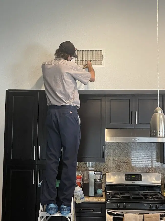 Technician inspecting an air vent during HVAC service in Snyderville